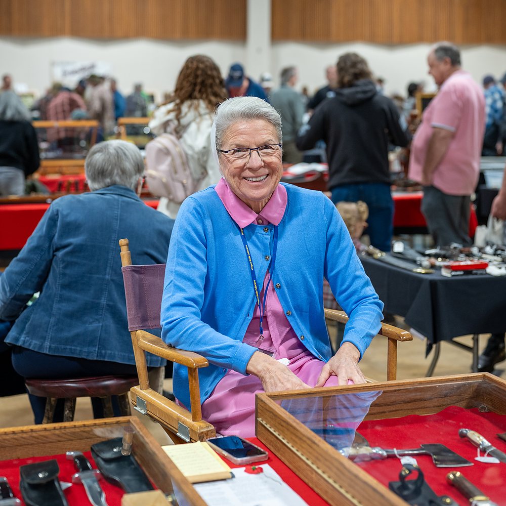 An exhibitor sits among her red display cases