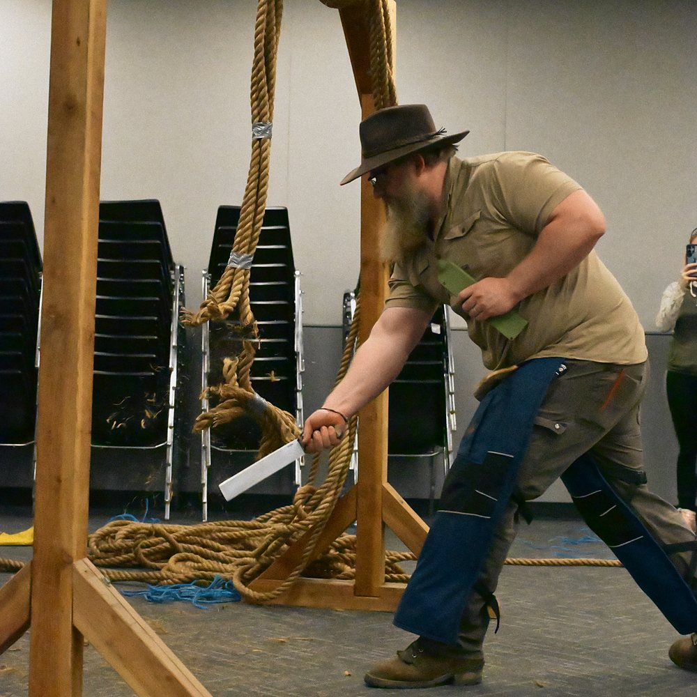 A competitor cuts through hanging rope in the rope cutting competition