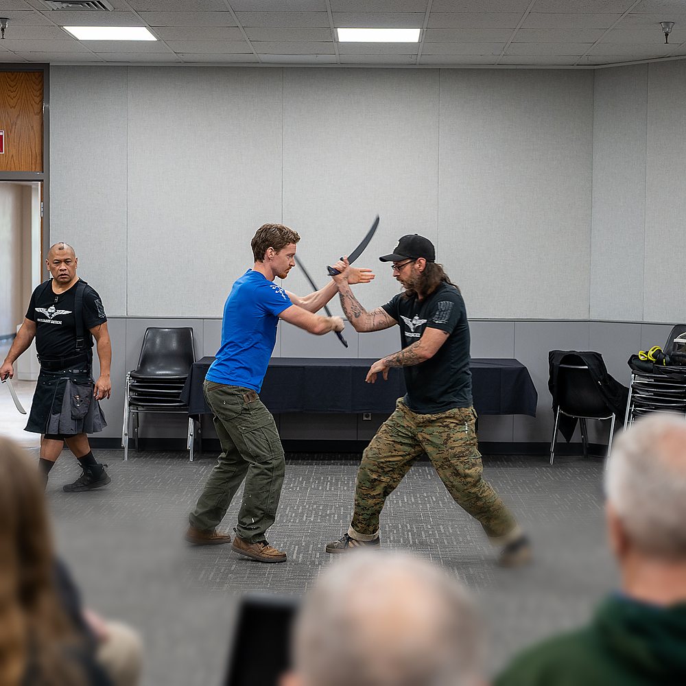 Two swordsmen give a sword demonstration to a seated audience
